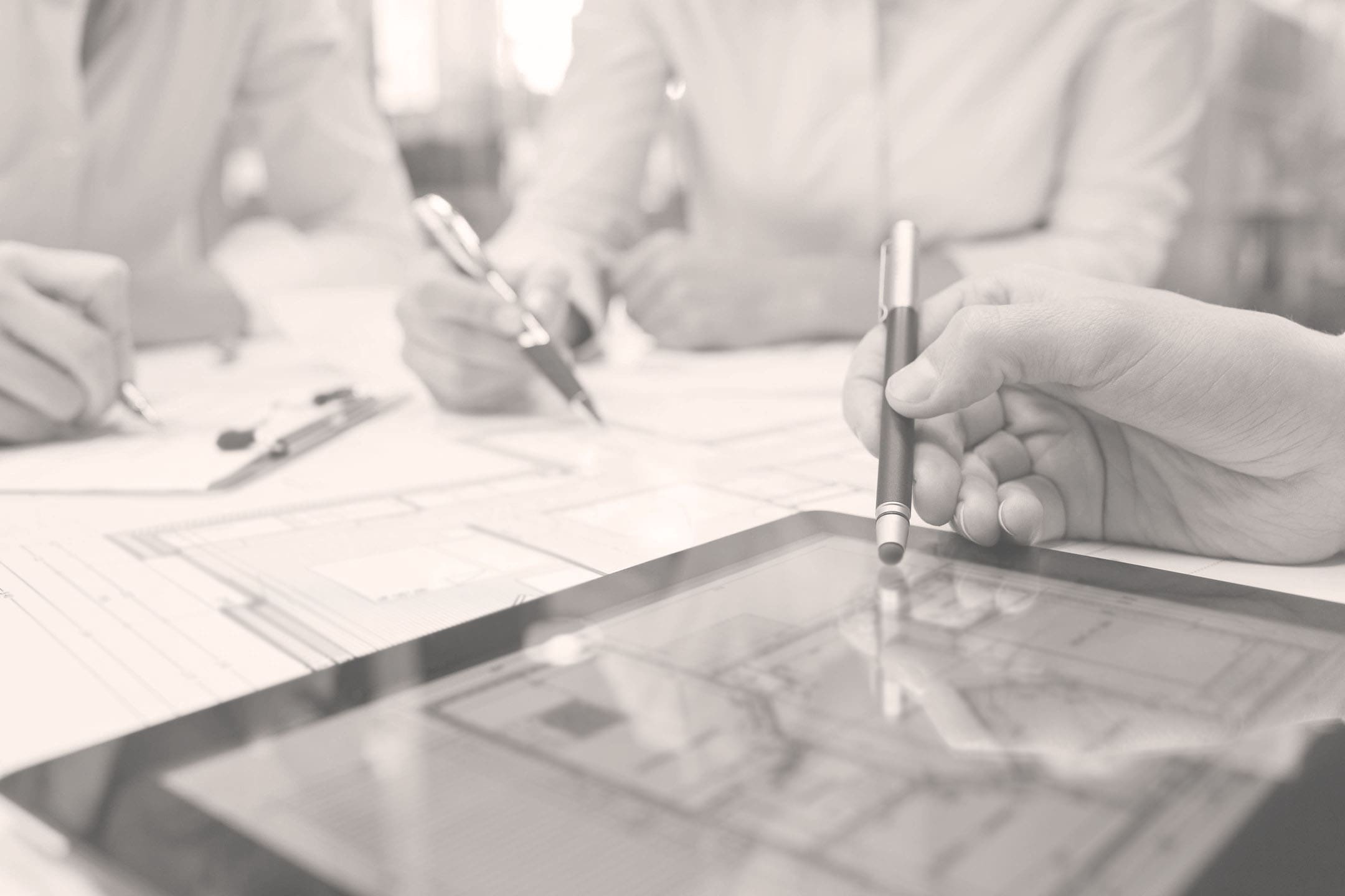 A person holding a pen and paper on top of a table.