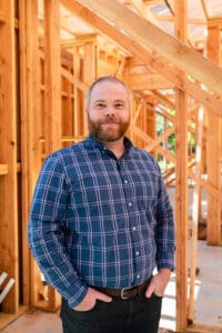 A man standing in front of some wood.